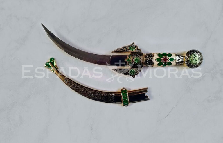 Daga árabe con hoja de acero inoxidable curvada y decorada, junto a empuñadura y vaina ornamentadas en tonos marfil, verde y rojo.
