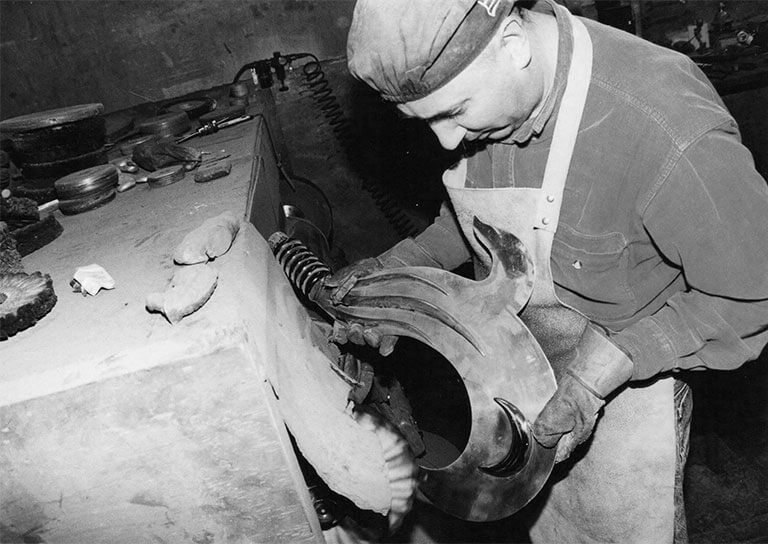 Paco Berenguer puliendo a mano el filo de una espada ornamental en su taller durante los años 90
